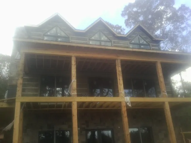 Dormers and porch framing on a large log home under construction — Roof Coating work by our crew in Navarre