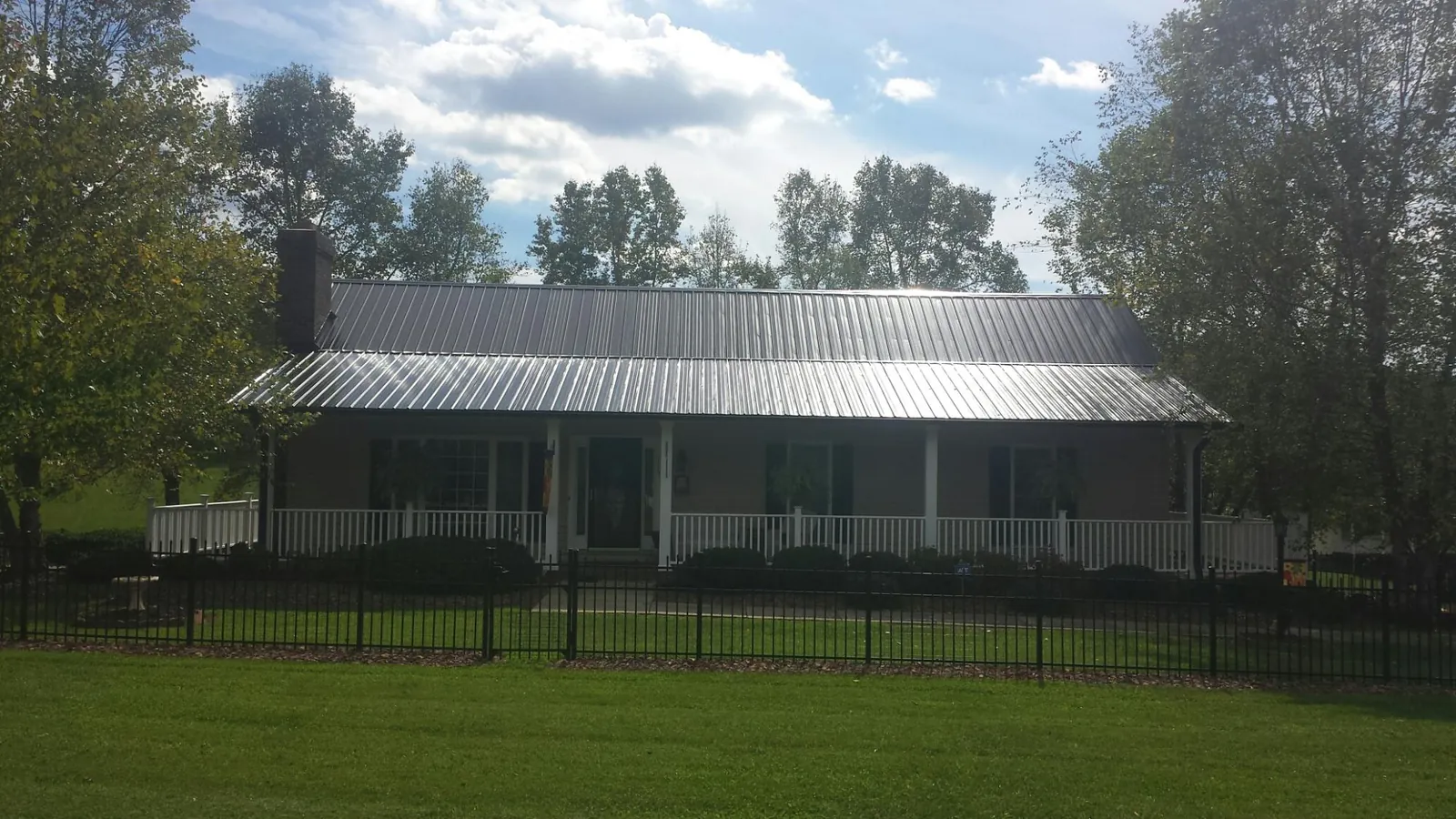Gray metal roof on a brick ranch with a full width front porch — Gutter Guard Installation work by our crew in Navarre